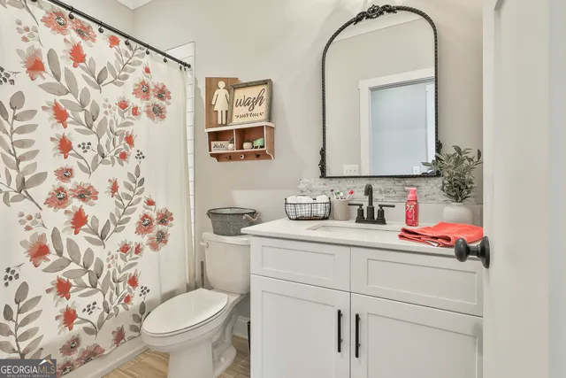 a bathroom with a granite countertop sink and a toilet