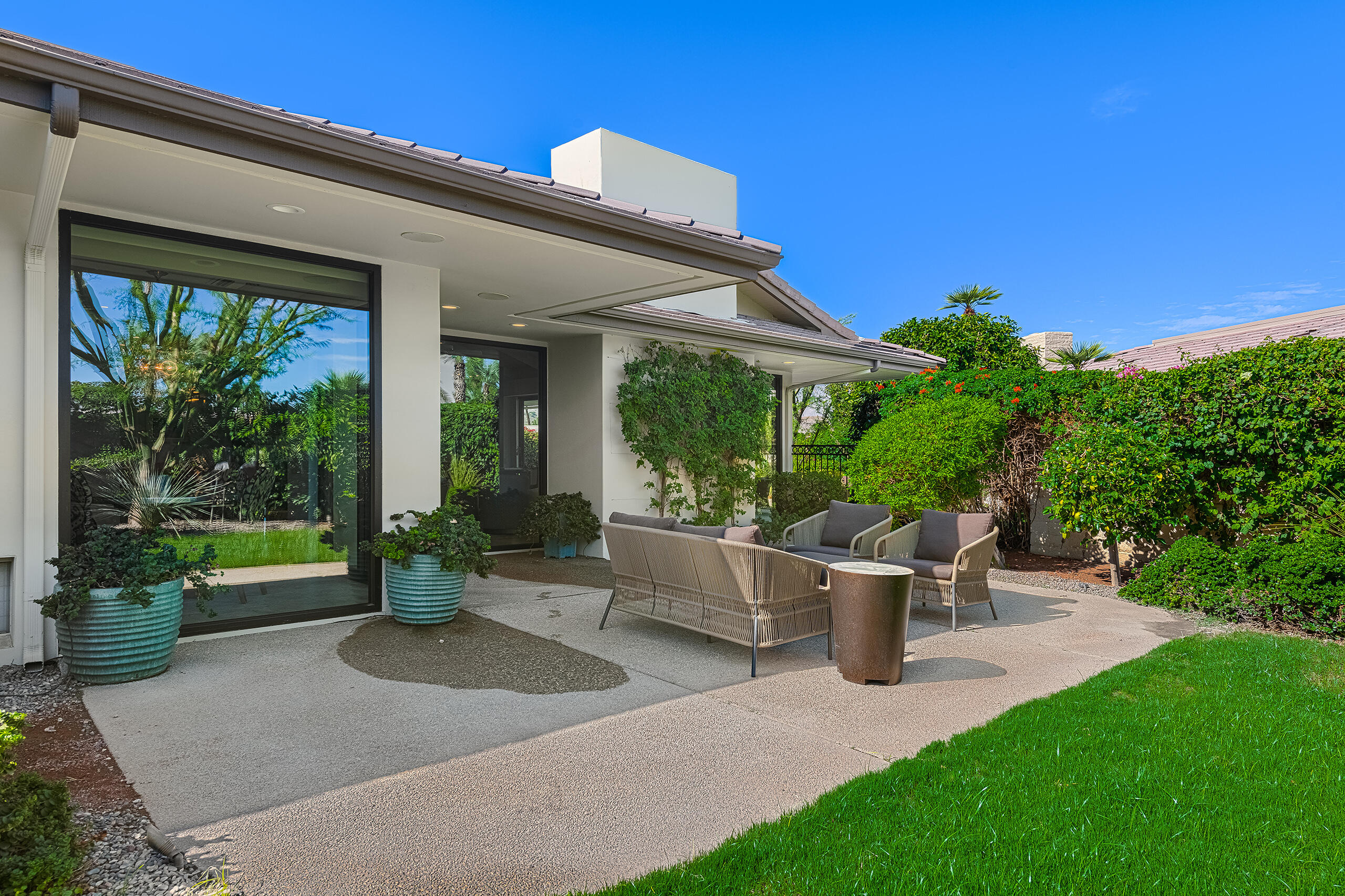 18 Creekside Drive Rancho Mirage, CA 92270 - Photo 23 of 40 a view of a patio with table and chairs potted plants and floor to ceiling window