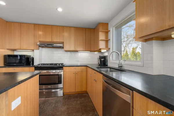 a kitchen with stainless steel appliances granite countertop a sink a stove and a microwave