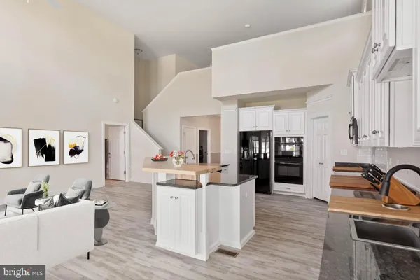 a living room with stainless steel appliances kitchen island furniture and a wooden floor