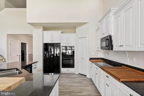 a large kitchen with stainless steel appliances kitchen island granite countertop a refrigerator and a sink