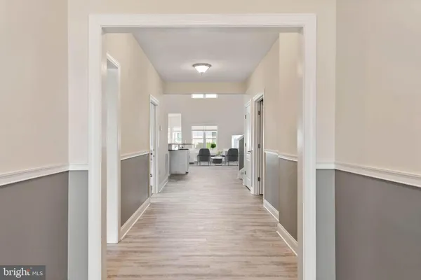 a view of a hallway with wooden floor cabinets and a living room