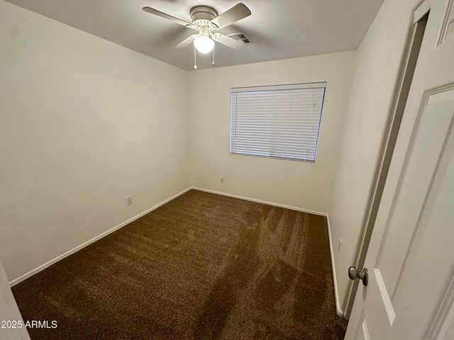 an empty room with a chandelier fan and a window