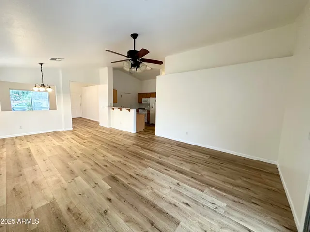 a view of empty room with wooden floor and ceiling fan
