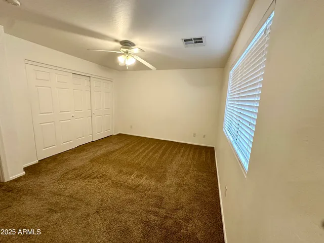 an empty room with a ceiling fan and wooden floor