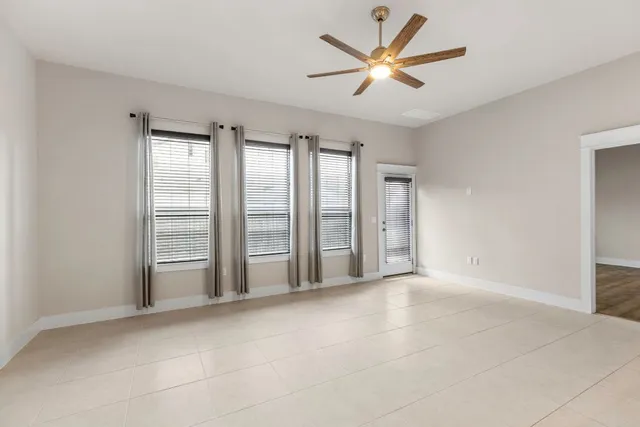 an empty room with windows and ceiling fan