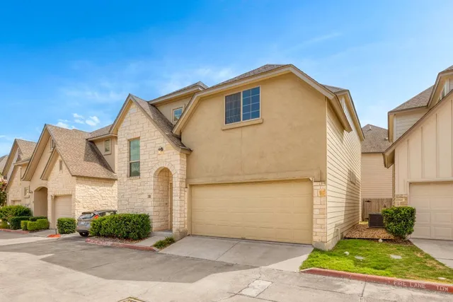 a view of a white house with a small yard and plants