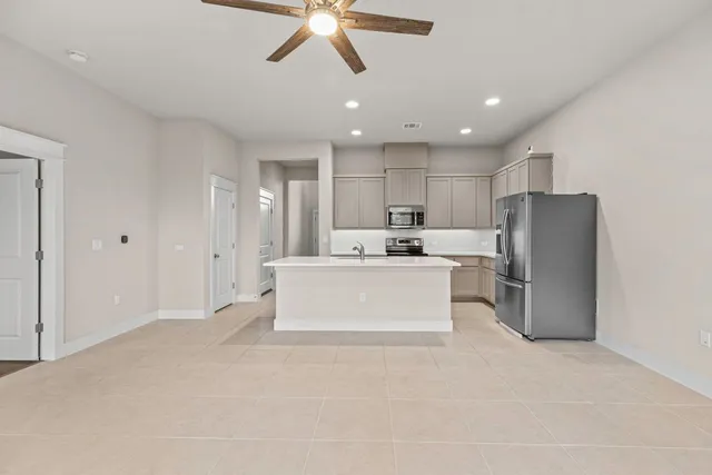 a view of kitchen with stainless steel appliances granite countertop a refrigerator a oven a white stove with white cabinets