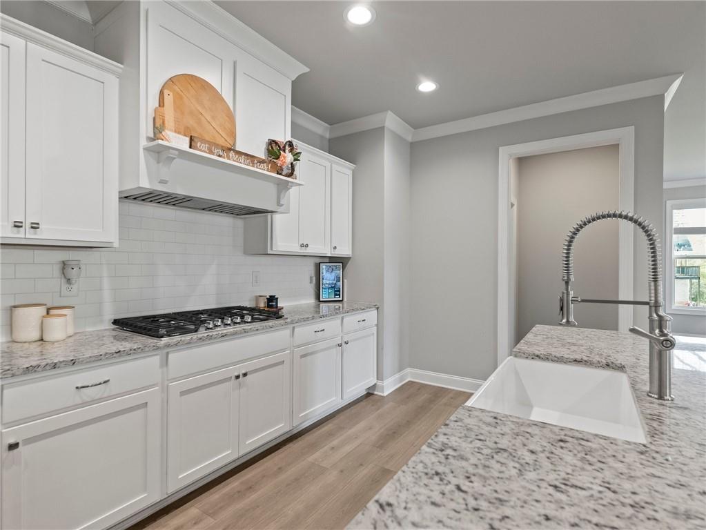 857 Champagne Lane Hoschton, GA 30548 - Photo 19 of 73 a kitchen with stainless steel appliances granite countertop a stove a sink and a white wooden cabinets