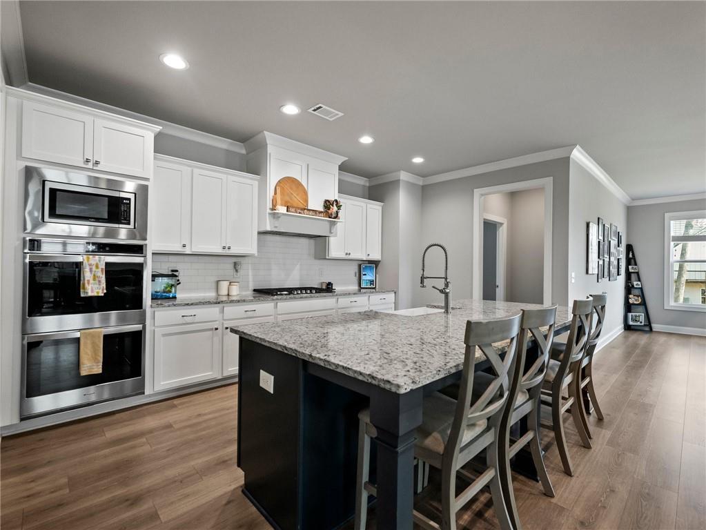 857 Champagne Lane Hoschton, GA 30548 - Photo 20 of 73 a kitchen with granite countertop white cabinets and stainless steel appliances