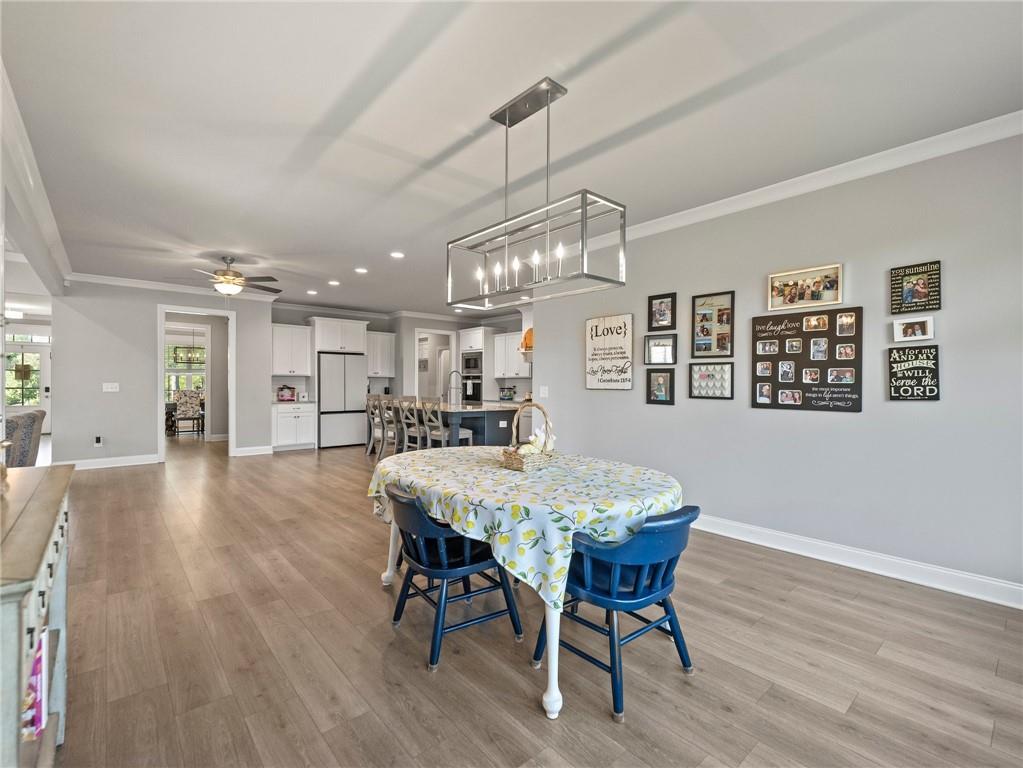 857 Champagne Lane Hoschton, GA 30548 - Photo 22 of 73 a dining room with wooden floor a chandelier a wooden table and chairs
