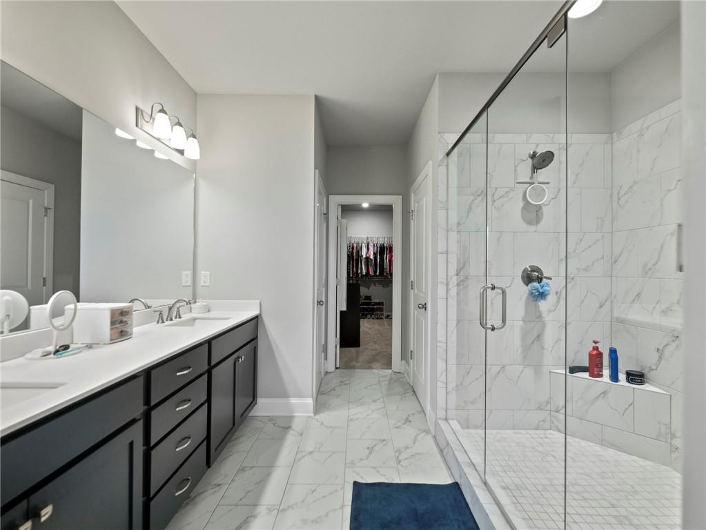 857 Champagne Lane Hoschton, GA 30548 - Photo 31 of 73 a bathroom with a double vanity sink a large mirror and shower