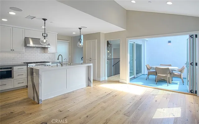 a kitchen with stainless steel appliances granite countertop a sink dishwasher a stove and a refrigerator with wooden floor