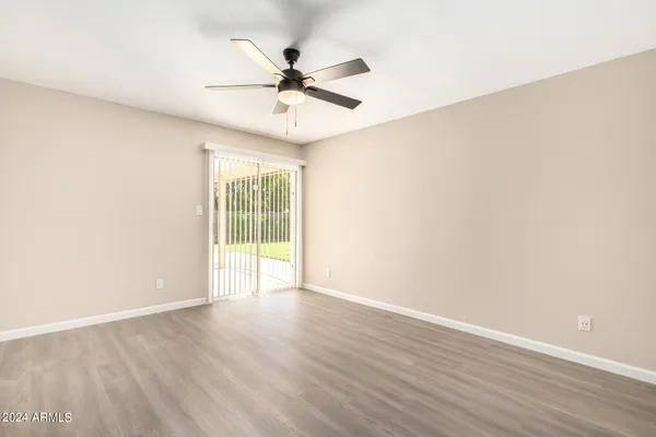 an empty room with wooden floor fan and windows