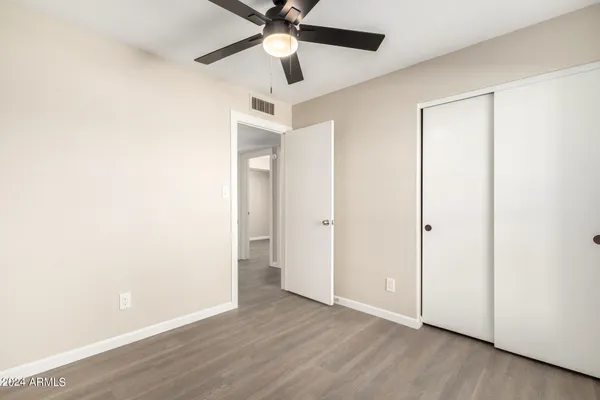 an empty room with wooden floor ceiling fan and windows