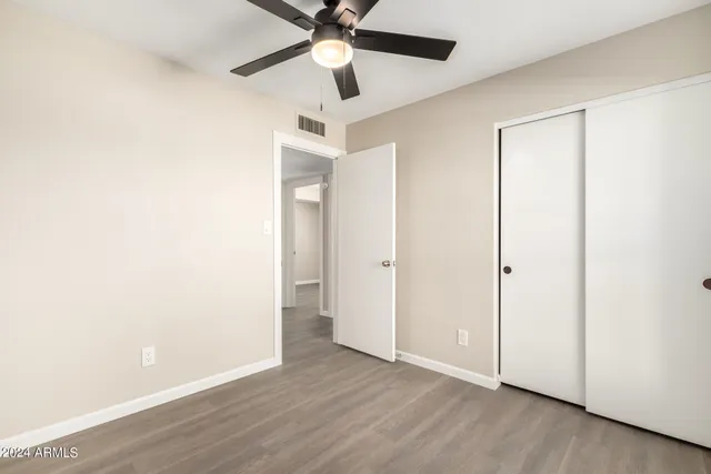 an empty room with wooden floor ceiling fan and windows