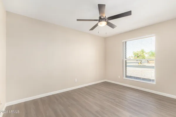 an empty room with wooden floor and ceiling fan