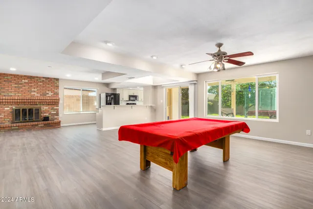 a room with pool table wooden floor and windows