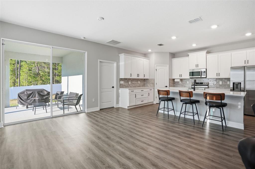 8549 Southwest 129 Lane Ocala, FL 34473 - Photo 13 of 31 a living room with stainless steel appliances a dining table wooden floor and a kitchen view