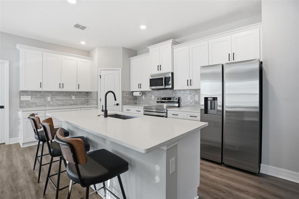 8549 Southwest 129 Lane Ocala, FL 34473 - Photo 10 of 31 a kitchen with stainless steel appliances a sink a stove a refrigerator with white cabinets and wooden floor