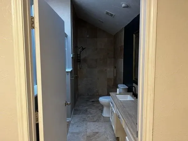 a bathroom with a granite countertop sink a toilet and shower