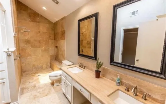 a bathroom with double vanity sinks a toilet a mirror and shower
