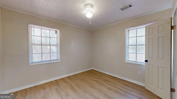 an empty room with wooden floor and windows