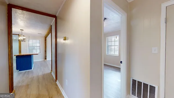 a view of a hallway with wooden floor and a bathroom