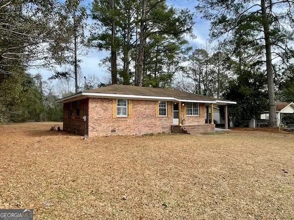 a front view of house with yard and trees in the background