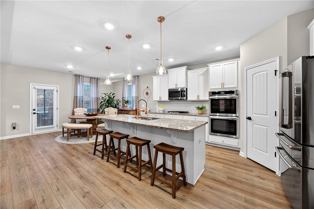 4863 Sultana Way Atlanta, GA 30331 - Photo 13 of 42 a kitchen with kitchen island stainless steel appliances a dining table chairs sink and stove top oven