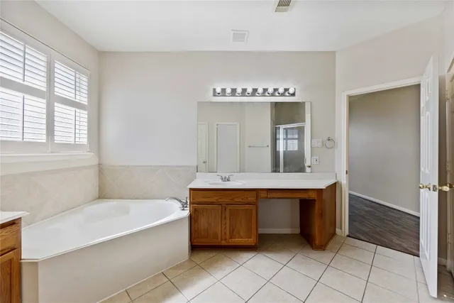 a spacious bathroom with a tub sink shower and mirror