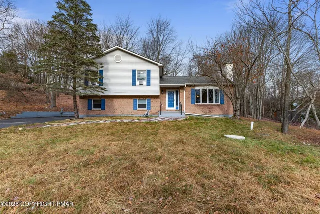 a view of a house with a yard and large tree