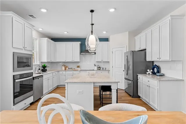 a large white kitchen with kitchen island white cabinets and wooden floor
