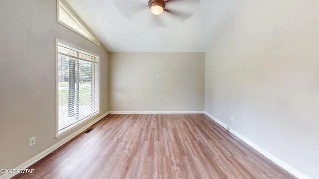 a view of an empty room with wooden floor and a window