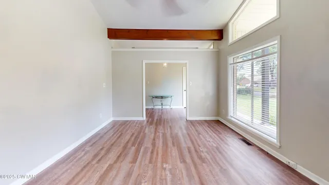 a view of an empty room with wooden floor and a window