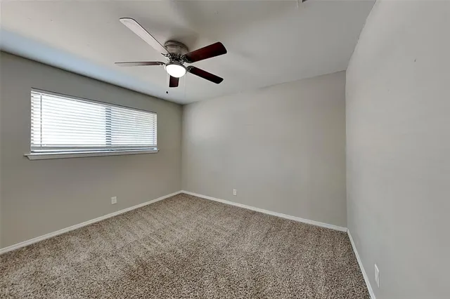 an empty room with a ceiling fan and window