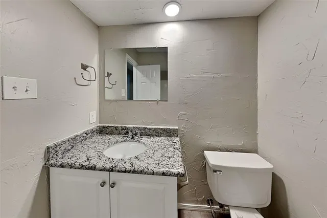 a bathroom with a granite countertop sink a toilet and mirror
