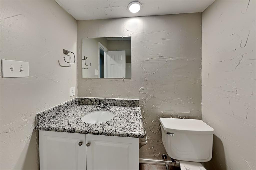 2611 Valley View Drive Corinth, TX 76210 - Photo 15 of 18 a bathroom with a granite countertop sink a toilet and mirror