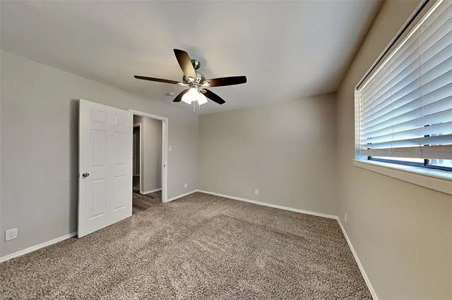 an empty room with a ceiling fan and window