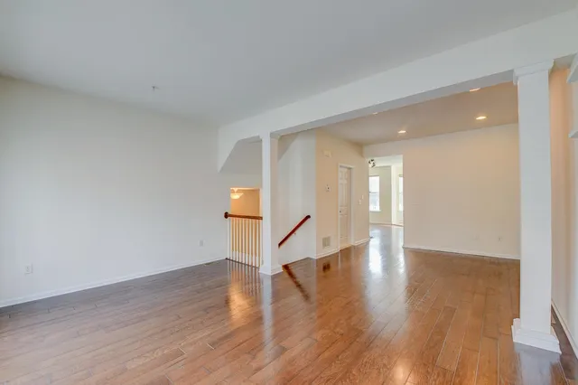 a view of an empty room with wooden floor and stairs