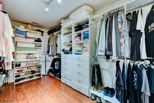 a view of walk in closet with clothes and shoes