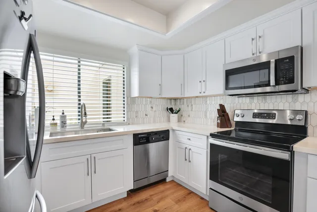 a kitchen with white cabinets stainless steel appliances and wooden floor