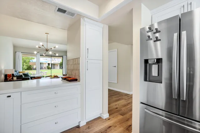 a dining room with wooden floor a chandelier a wooden table and chairs