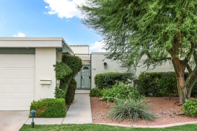 a front view of a house with a yard and potted plants