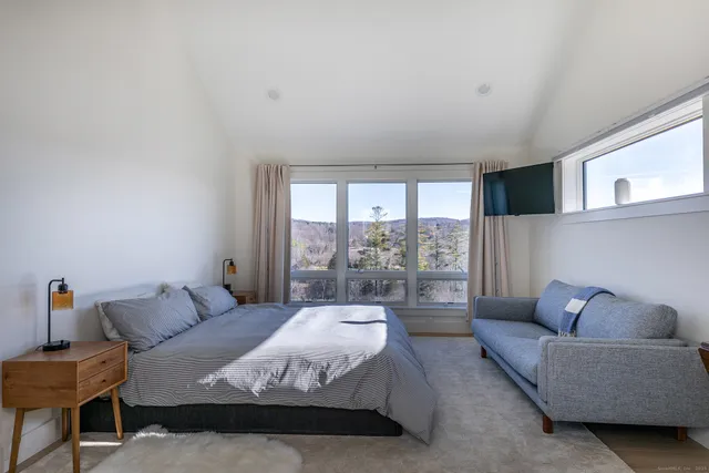 a spacious bedroom with a bed and glass window