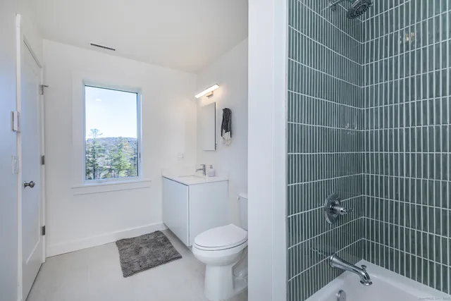 a bathroom with a toilet a sink a window and shower