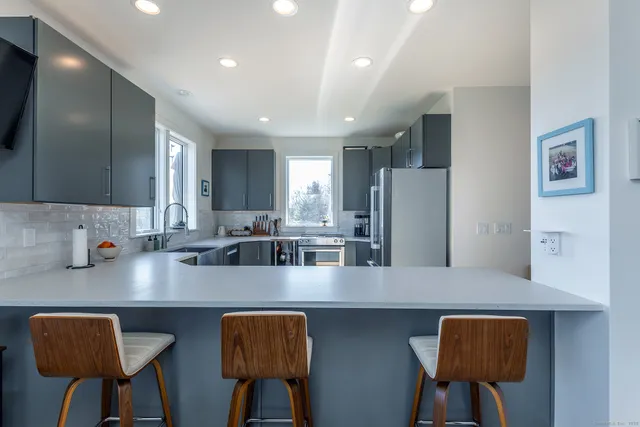 a kitchen with stainless steel appliances granite countertop a table chairs in it and wooden floors