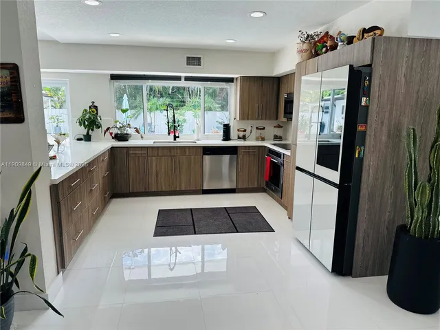 a kitchen with stainless steel appliances kitchen island granite countertop a refrigerator and a sink
