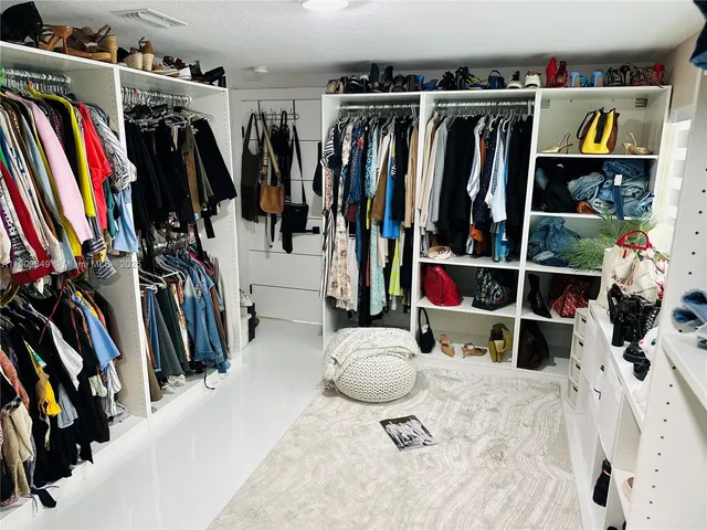 a view of walk in closet with clothes and shoes