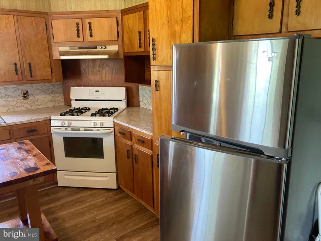 a view of a kitchen with kitchen island a large window a sink and a counter space